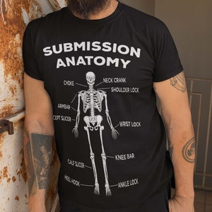May include: A black t-shirt featuring a white skeleton graphic and the text "Submission Anatomy" with various submission holds labelled on the skeleton.