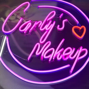 May include: Pink neon sign with the text "Carly's Makeup" and a pink heart.