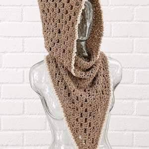 May include: A light brown crochet hooded cowl featuring an openwork stitch pattern and a delicate cream-colored scalloped edge trim. The garment is designed with a pointed front drape and a structured hood, showcasing a detailed yarn texture.
