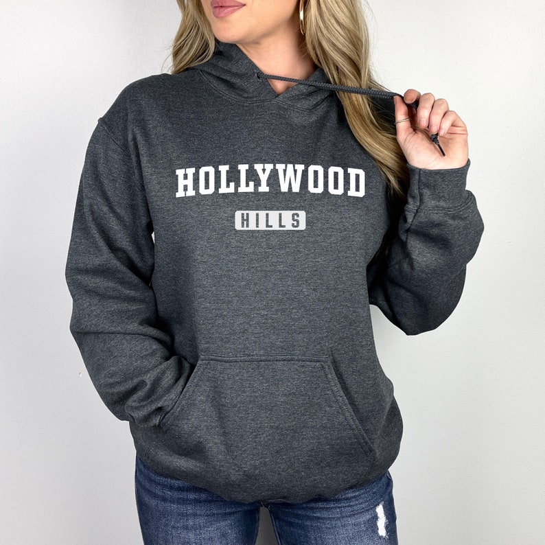 May include: A dark gray hooded sweatshirt with the text "HOLLYWOOD HILLS" in white lettering.