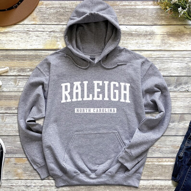 Peut inclure: Un sweat &agrave; capuche gris avec le texte "RALEIGH NORTH CAROLINA" imprim&eacute; en blanc sur le devant.