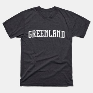 May include: A dark heather grey t-shirt with the word "GREENLAND" printed in white on the front.