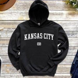 Pu&ograve; includere: Felpa con cappuccio nera con testo bianco che recita "KANSAS CITY KS" sul davanti.