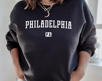 Puede incluir: Sudadera negra con texto blanco que dice "PHILADELPHIA PA".