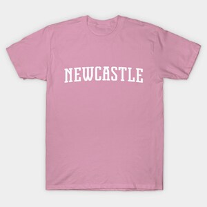 K&ouml;nnte beinhalten: Ein pinkfarbenes T-Shirt mit dem Wort "NEWCASTLE" in wei&szlig; auf der Vorderseite.