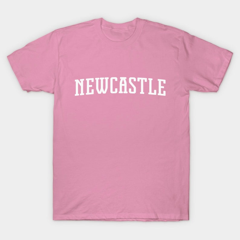 K&ouml;nnte beinhalten: Ein pinkfarbenes T-Shirt mit dem Wort "NEWCASTLE" in wei&szlig; auf der Vorderseite.