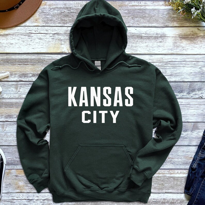 May include: A dark green hooded sweatshirt with the text "KANSAS CITY" in white lettering.