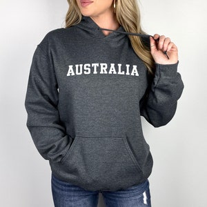 Puede incluir: Una sudadera con capucha gris oscuro con la palabra "AUSTRALIA" impresa en blanco en la parte delantera.