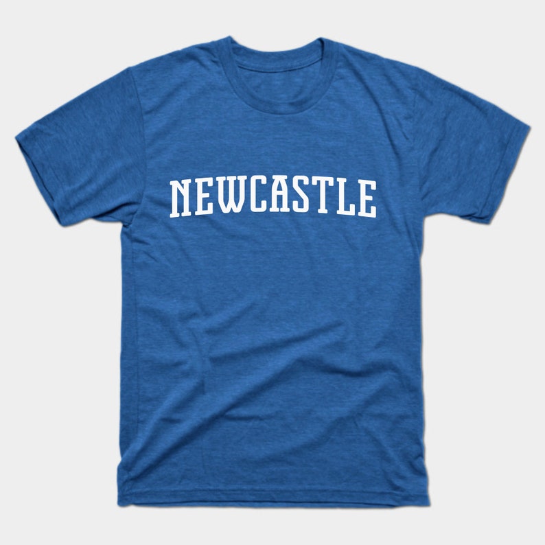 K&ouml;nnte beinhalten: Ein k&ouml;nigsblaues T-Shirt mit dem Wort "NEWCASTLE" in wei&szlig; auf der Vorderseite.
