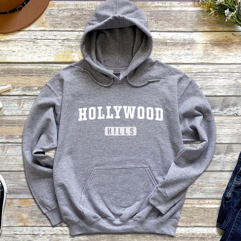 May include: A gray hooded sweatshirt with the text "HOLLYWOOD HILLS" printed in white on the front.