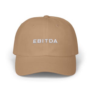 May include: A tan baseball cap with the word "EBITDA" embroidered in white on the front.