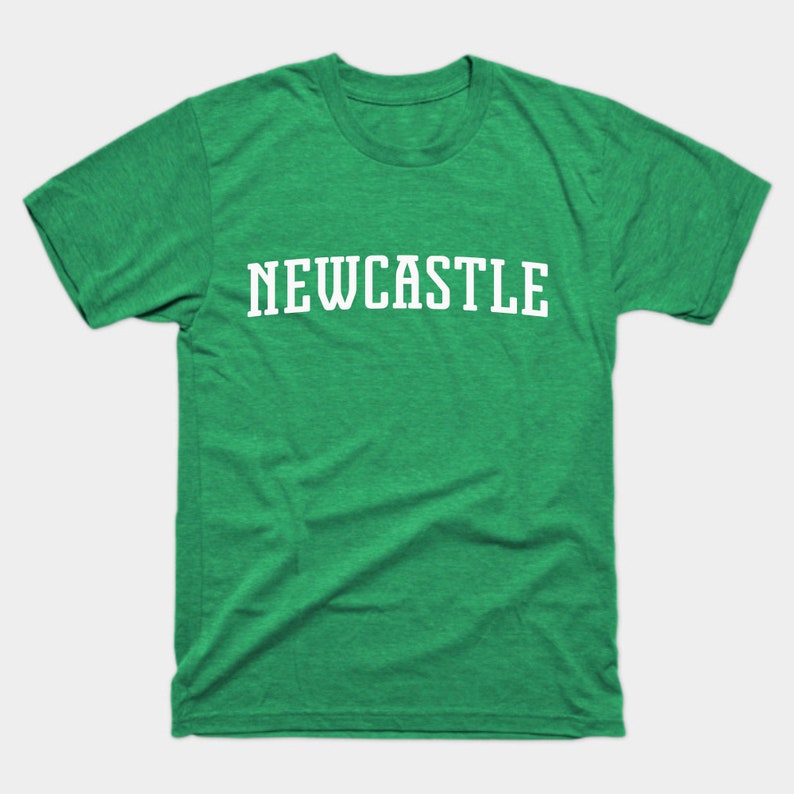 K&ouml;nnte beinhalten: Ein gr&uuml;nes T-Shirt mit dem Wort "NEWCASTLE" in wei&szlig; auf der Vorderseite.