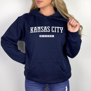 May include: A navy blue hooded sweatshirt with white text that reads "KANSAS CITY MISSOURI".