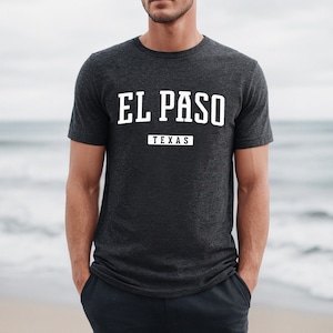 Może przedstawiać: Szary t-shirt w ciemnym melanżu z białym nadrukiem graficznym z napisem "EL PASO TEXAS" w stylu vintage.