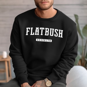 May include: Black sweatshirt with white text that reads "FLATBUSH" and "BROOKLYN" in a vintage collegiate font.