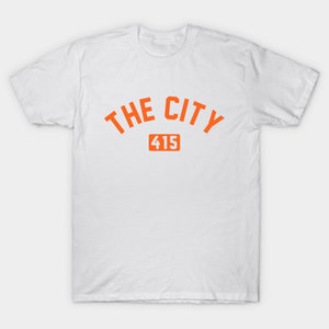 Op de afbeelding: Wit T-shirt met oranje tekst "THE CITY 415".
