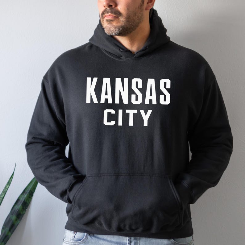 May include: Black hooded sweatshirt with white text that reads "KANSAS CITY".