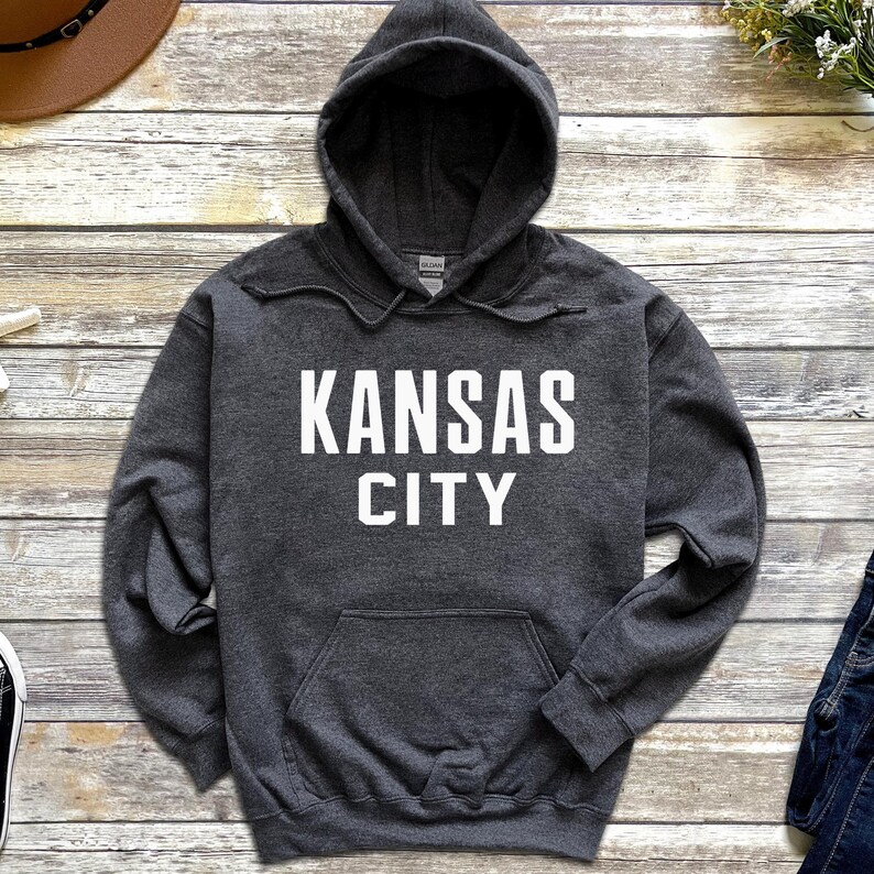 May include: A dark gray hooded sweatshirt with a white print that says "KANSAS CITY".