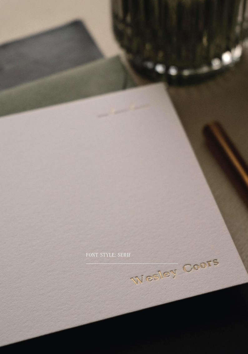 Puede incluir: Una tarjeta de papeler&iacute;a de color crema claro con el nombre Wesley Coors grabado en letras doradas. La tarjeta tiene una superficie texturizada e incluye el texto FONT STYLE: SERIF impreso en letras negras peque&ntilde;as sobre el nombre.