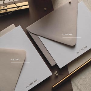 May include: Two white stationery cards with matching beige envelopes, one in portrait and one in landscape orientation. Each card features the black printed text 'xo, NEOLANI' in the bottom corner. The set includes a gold pen and a glass holder.