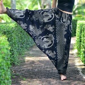 May include: Black pants with a white koi fish and floral print. The pants are loose fitting and have a wide leg.
