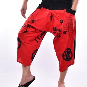 May include: Red and black patterned pants with a wide leg and elastic waistband. The pants have a black drawstring and a mesh pocket on the side.