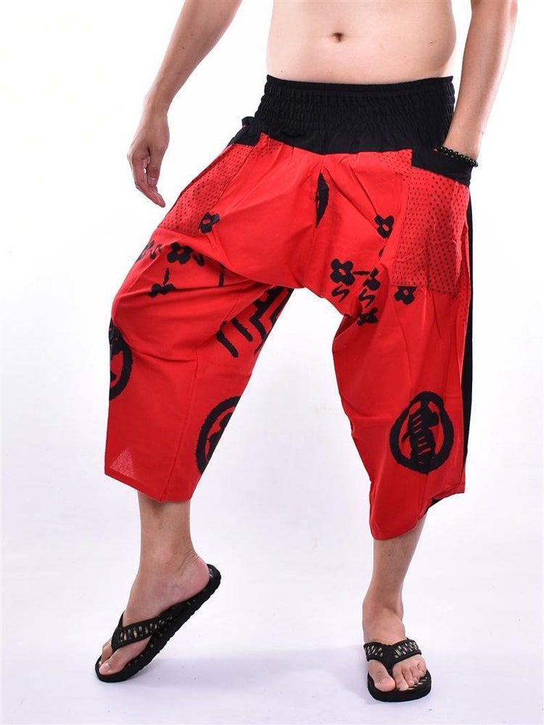 May include: Red and black patterned pants with a wide leg and elastic waistband. The pants have a black drawstring and a mesh pocket on the side.