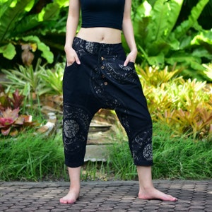 May include: Black cotton trousers with a floral pattern. The trousers have a loose fit and a drawstring waist.