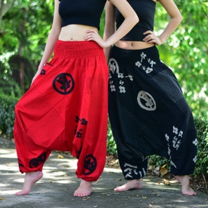 Puede incluir: Dos pares de pantalones holgados con estampado y cintura el&aacute;stica. Un par es rojo con dise&ntilde;os negros y el otro es negro con dise&ntilde;os blancos.