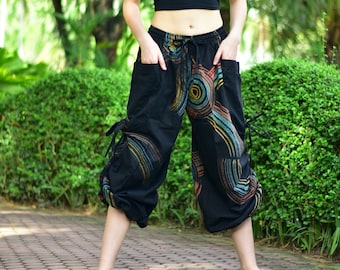 May include: Black harem trousers with colourful circular patterns and side pockets. The trousers have a drawstring waist and ties at the ankles. The design features shades of blue, yellow, and orange.