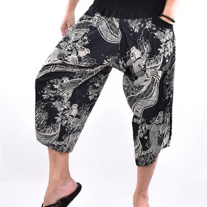 Może przedstawiać: Czarno-białe spodnie z nadrukiem w kształcie ryb. Spodnie mają szerokie nogawki i elastyczny pas.