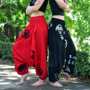 Puede incluir: Dos personas con pantalones holgados y estampados. Un par es rojo con caracteres kanji negros y el otro es negro con dise&ntilde;os florales blancos.