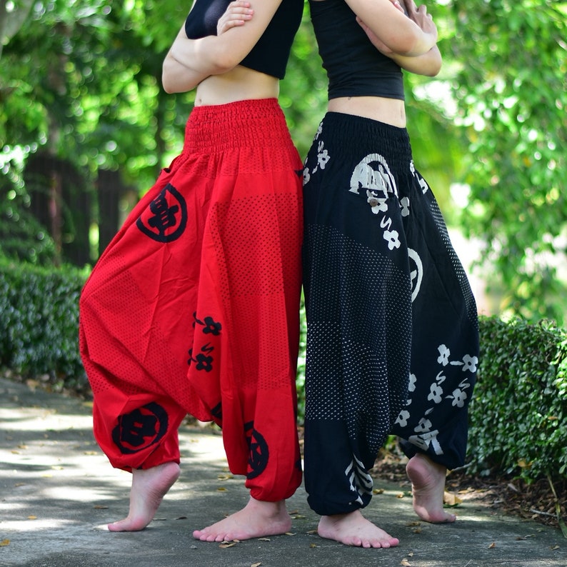 Puede incluir: Dos personas con pantalones holgados y estampados. Un par es rojo con caracteres kanji negros y el otro es negro con dise&ntilde;os florales blancos.