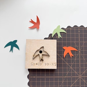 May include: A wooden die with a bird-shaped cutout and several colorful leather bird cutouts. The die has the text "SX-44 40*45" etched on it. The leather birds are in shades of teal, orange, red, and green.