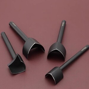 May include: Four black leathercraft tools with curved cutting edges and long handles. The tools are labeled with sizes: 25mm, 35mm, and 40mm. The tools are arranged on a burgundy surface.