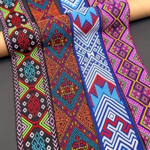 May include: Four strips of woven fabric trim featuring intricate geometric patterns. The designs include diamonds, chevrons, and floral motifs in vibrant colors such as neon green, bright blue, magenta, orange, red, and black on a dark background.