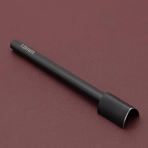 May include: A black leathercraft tool with a cylindrical handle and a curved cutting edge. The text "15mm" is printed on the handle. The tool is designed for cutting leather and similar materials.