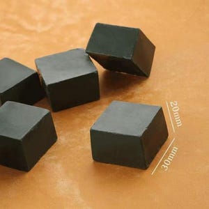 Peut inclure: Plusieurs objets sombres en forme de cube gris sont disposés sur une surface brun clair. Un cube est dimensionné à 20 mm x 30 mm. Les cubes semblent être faits d'un matériau solide et mat.