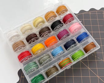 May include: A clear plastic organizer filled with spools of colorful thread. The thread colors include white, yellow, brown, red, pink, blue, green, and orange. The spools are neatly arranged in individual compartments, ideal for sewing and crafting projects.