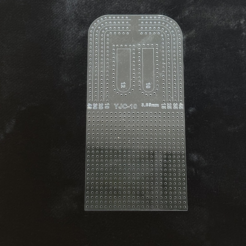 Peut inclure: Un gabarit en acrylique transparent pour le travail du cuir, pr&eacute;sentant une disposition en forme de U avec de nombreux trous pr&eacute;-perc&eacute;s pour la couture. Le gabarit porte le texte YJC-10 et 3.85mm, ainsi que les chiffres 10, 12, 15, 20, 25, 30, 35, 40 et 45.