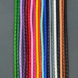 Puede incluir: Una colección de cordones trenzados dispuestos verticalmente en un espectro de colores que incluye verde, morado, rojo, rosa, amarillo, naranja, azul claro, azul oscuro, gris, blanco, negro, beige y marrón. Cada cordón tiene una textura tejida.