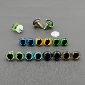 May include: A collection of colorful plastic craft eyes in various sizes and colors, including blue, yellow, green, and brown. Some eyes have screw-in posts, while others have flat backs. A white plastic washer is also included.