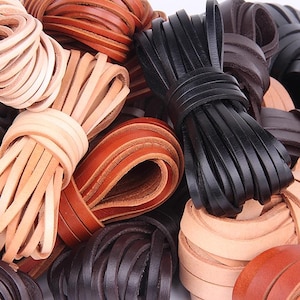 Könnte beinhalten: Nahaufnahme von verschiedenen Bündeln aus Lederriemen in den Farbtönen Beige, Braun und Schwarz. Die Lederriemen sind eng gerollt und scheinen für die Verwendung in der Herstellung oder anderen Projekten bereit zu sein. Das Bild zeigt die verschiedenen Farben und Texturen des Leders.