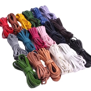 Könnte beinhalten: Eine Sammlung farbiger Lederschnüre in verschiedenen Farbtönen, darunter Rot, Braun, Gelb, Grün, Blau, Lila, Rosa und Schwarz. Die Schnüre sind gebündelt und zeigen ihre Textur und Farbvariationen. Ideal für Bastelarbeiten und Schmuckherstellung.