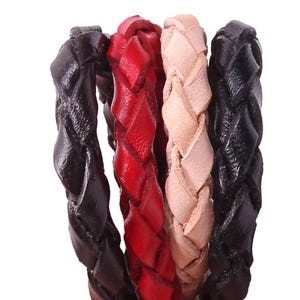 May include: Close-up of four braided leather bracelets in varying colours. The bracelets are in shades of black, red, tan, and dark brown. The leather is textured and the braids are tightly woven, showcasing a handcrafted aesthetic.