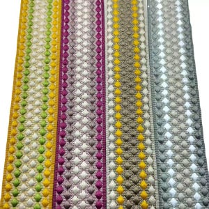 May include: Four vertical strips of decorative woven trim featuring a repeating diamond pattern. The strips display colour combinations of lime green and yellow, magenta and light purple, yellow and beige, and grey and white with textured stitching.