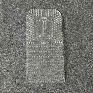 Peut inclure: Un gabarit en acrylique transparent pour le travail du cuir, dot&eacute; d'un bord sup&eacute;rieur arrondi, de nombreux trous de couture pr&eacute;-perc&eacute;s et de marquages grav&eacute;s incluant 6mm, 10, 12 et le code mod&egrave;le ABX-01 pour un alignement pr&eacute;cis.