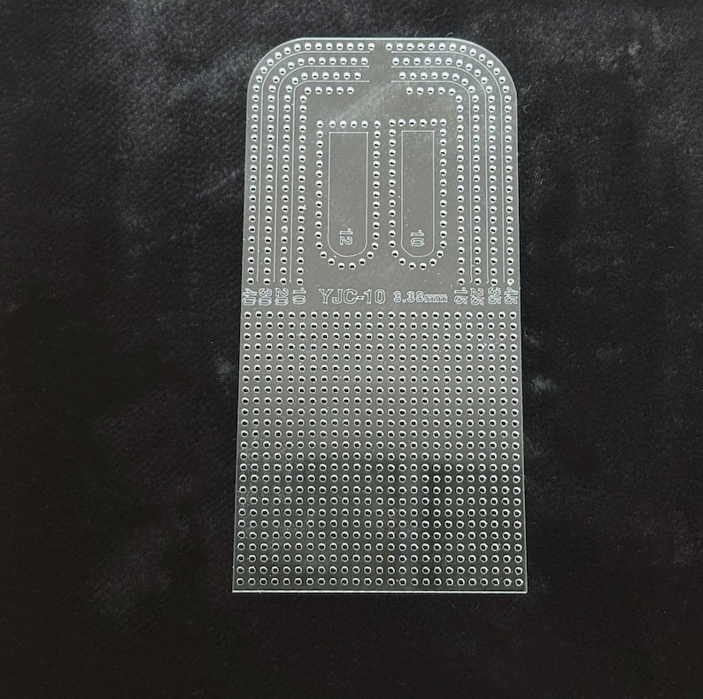 Peut inclure: Un gabarit en acrylique transparent pour le travail du cuir, dot&eacute; d'un sommet arrondi et d'une base rectangulaire. L'outil porte l'inscription YJC-10 3.38mm et comporte de nombreux trous perc&eacute;s avec pr&eacute;cision en rang&eacute;es et en U.