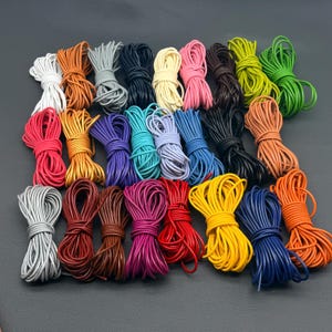 Op de afbeelding: Een verzameling van talloze bundels rond koord in een grote verscheidenheid aan effen kleuren, waaronder wit, oranje, grijs, zwart, crème, roze, bruin, limoengroen, felgroen, rood, geel, paars, turquoise, lichtblauw en donkerblauw.