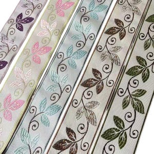 May include: Five strips of decorative ribbon featuring a repeating embroidered vine pattern with leaves in varying colours including purple, pink, light blue, brown, and green, all set against a light-coloured, smooth, satin-like fabric background.